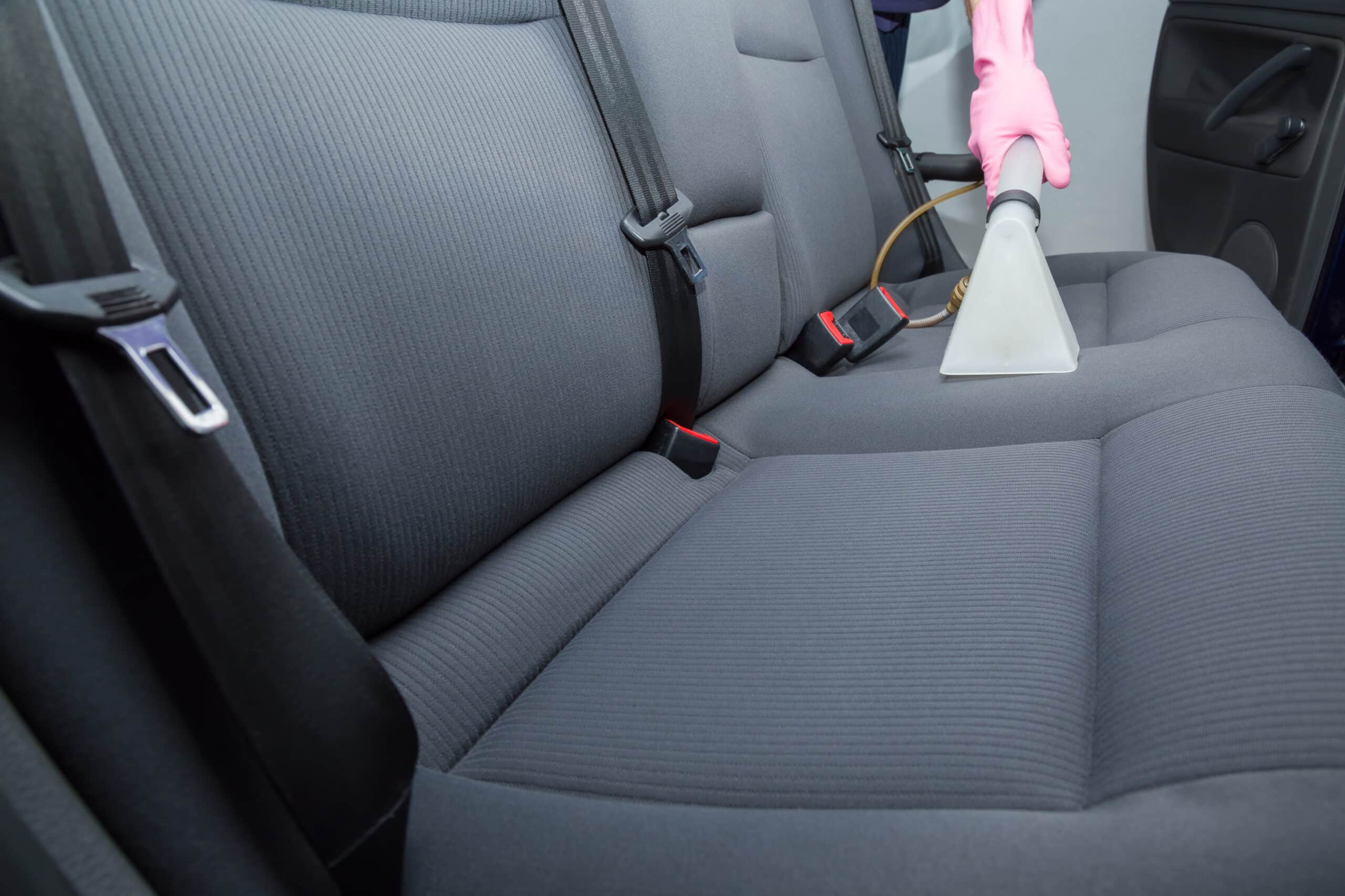 Lavage voiture haute pression : rinçage et mousse Lavage haute pression d'une voiture noire savonneuse sous un ciel bleu, l'eau mousse sur le capot et le pare-chocs.