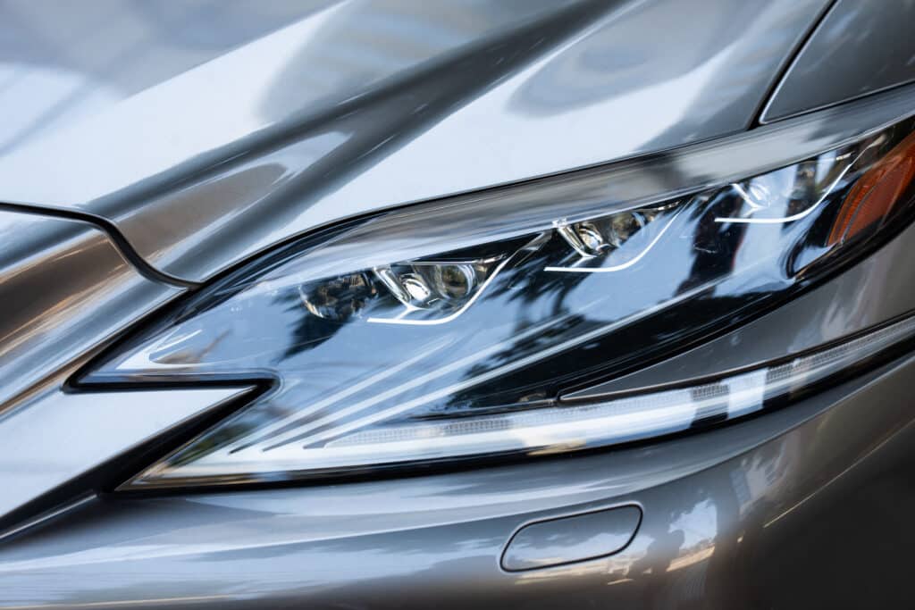 Phare Avant LED Voiture Luxe, Détail Design Gris Gros plan sur le phare avant LED d'une voiture gris métallisé, montrant la signature lumineuse et les reflets de l'environnement.